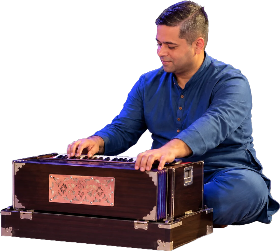 A musician in a blue kurta playing the harmonium